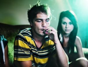 Ein Jugendlicher raucht bei einer Party einen Joint. Foto: Shutterstock