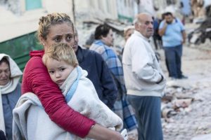 Eine Mutter mit Kind kann es noch nicht richtig fassen: Ihr Heimatort wurde völlig zerstört. Foto: epa