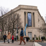 „Größenwahn des US-Präsidenten“: Großes Banner mit Porträt von Donald Trump am Justizministerium